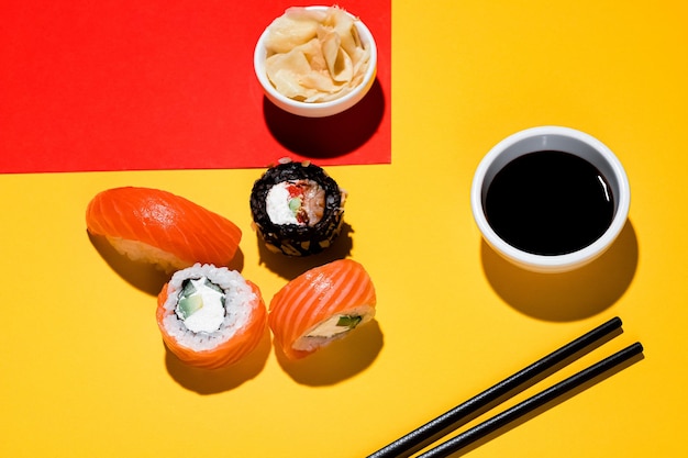 Sushi and rolls on a colored background, soy sauce, ginger. With a hard light