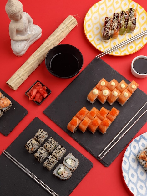 Sushi rolls on colored plates on a red background