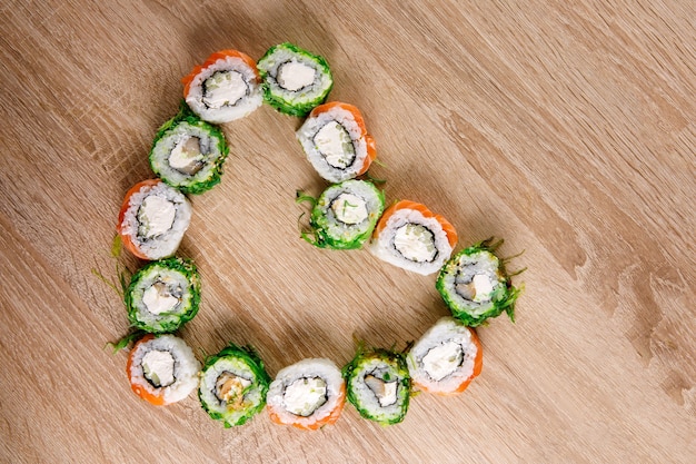 Sushi rolls lay on the table in the shape of a heart. Holiday set for St. Valentines Day. Top view.