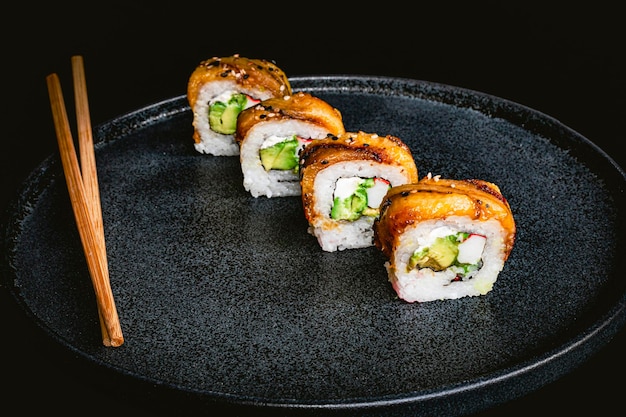 Photo sushi rolls lined up on a blue plate with chopsticks delicious japanese cuisine