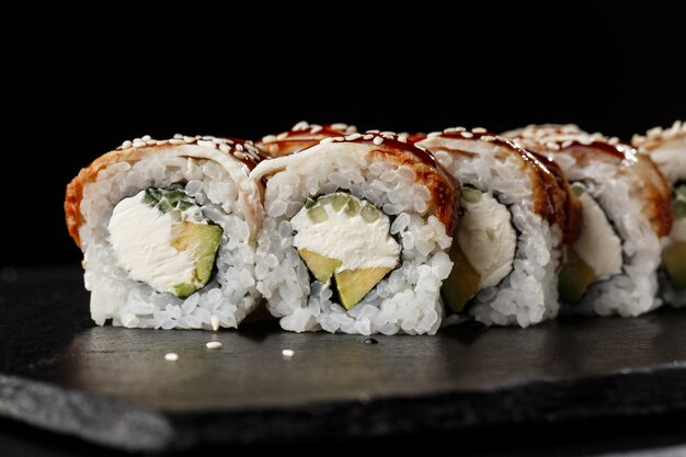 Sushi Rolls met komkommer, avocado, paling en roomkaas binnen op zwart
