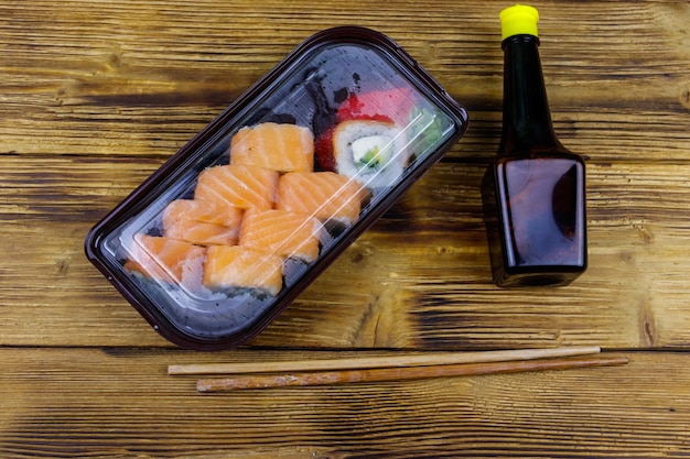 Sushi rolls Philadelphia in plastic box on wooden table Top view