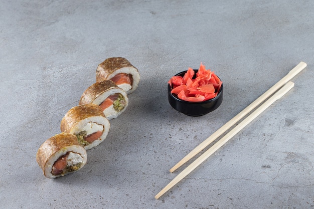 Rotoli di sushi, salsa di soia, wasabi e zenzero sott'aceto su fondo di pietra.