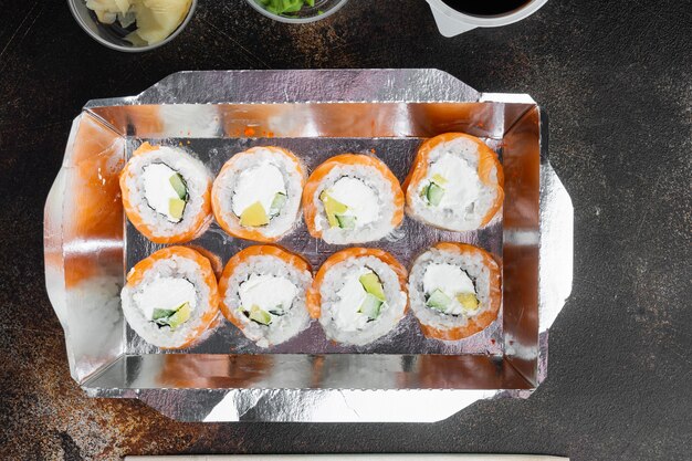 Sushi rolls in takeaway container set, on old dark rustic