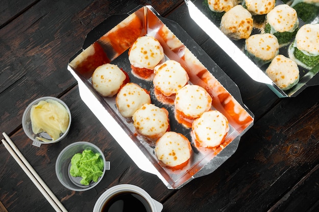 Sushi rolls in takeaway container set, on old dark  wooden table