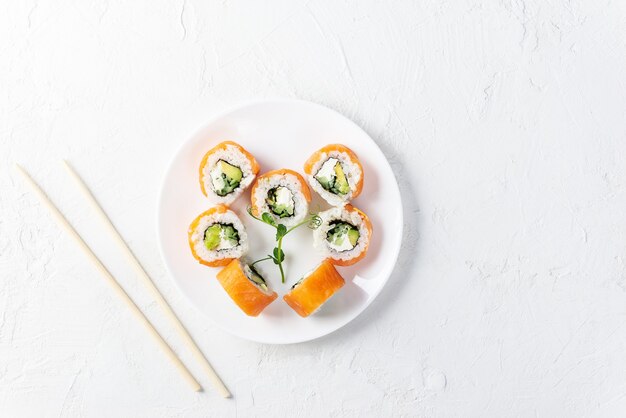 Rotoli di sushi per san valentino sotto forma di un cuore su un piatto bianco.