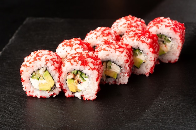 Sushi Rolls with avocado, eel, cucumber and cream cheese inside on black 