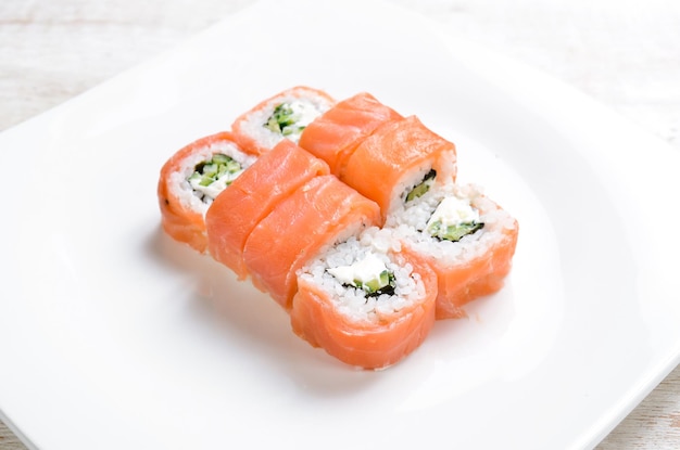 Sushi rolls with avocado and salmon on a white plate Top view On a white background