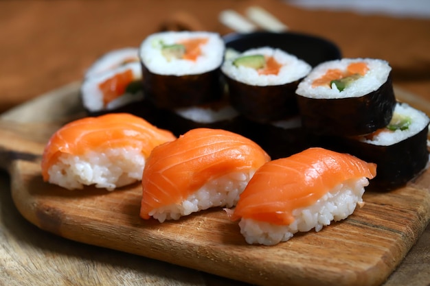 Sushi and rolls with avocado and salmon on a wooden board