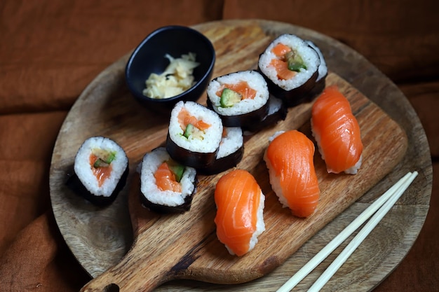Sushi and rolls with avocado and salmon on a wooden board
