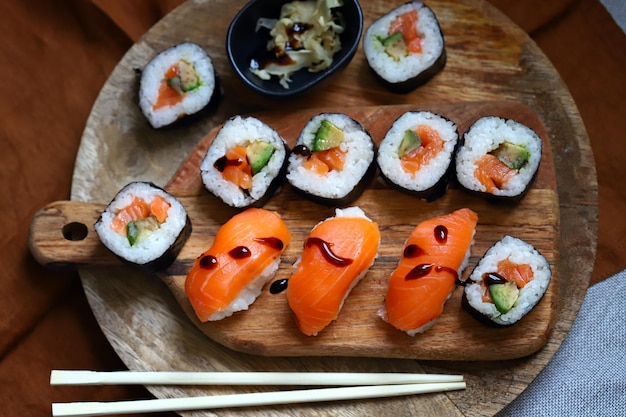 Sushi and rolls with avocado and salmon on a wooden board