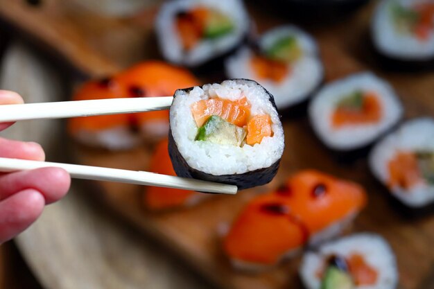 Sushi and rolls with avocado and salmon on a wooden board