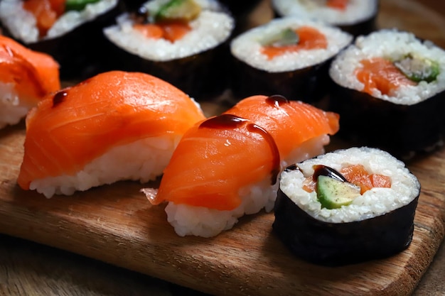 Sushi and rolls with avocado and salmon on a wooden board