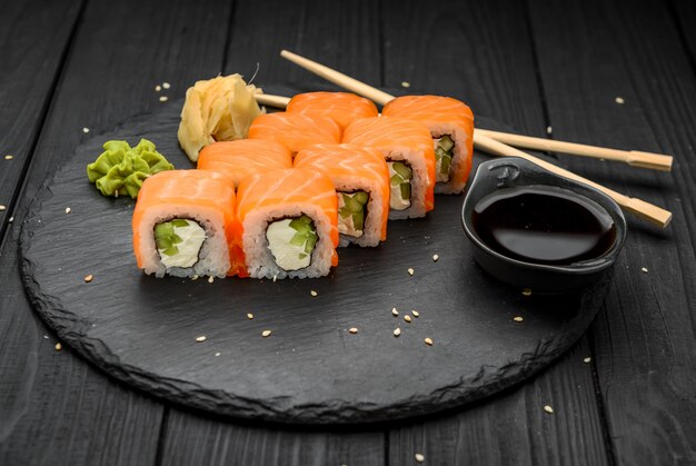 Rotoli di sushi con formaggio philadelphia, salmone e tonno sul nero