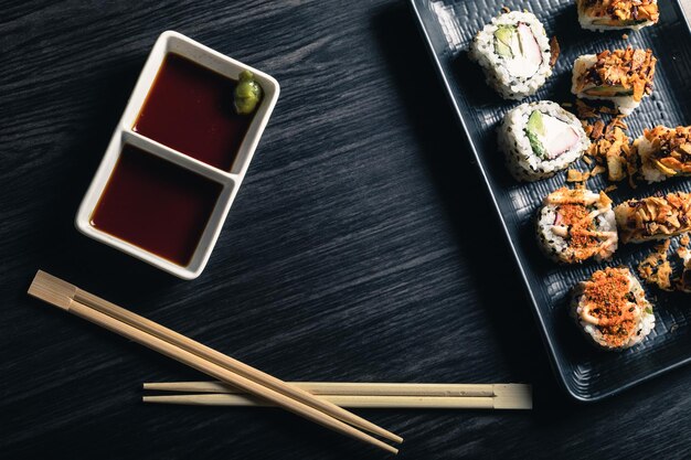 Sushi rolls with chopsticks and soy sauce on dark background Copy space