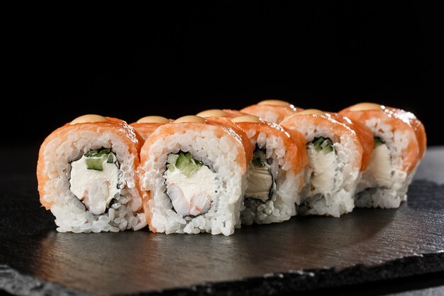 Sushi Rolls with cucumber, shrimp, salmon and Cream Cheese inside on black