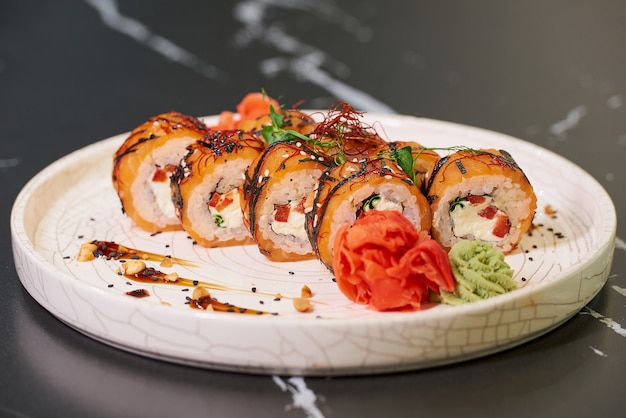 Foto rotoli di sushi con salmone, formaggio philadelphia e tonno su un piatto di ceramica bianca