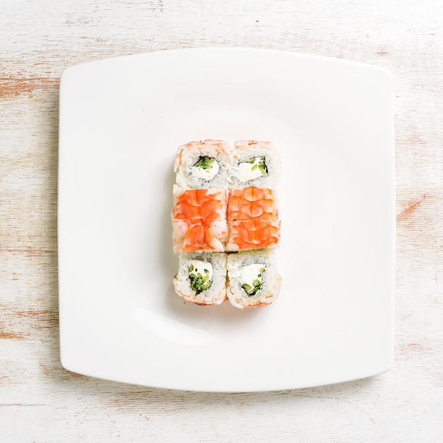 Sushi rolls with salmon on a white plate. Top view. On a white background.