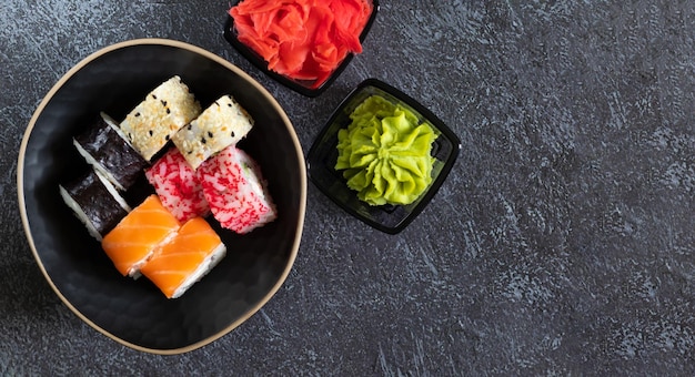 Sushi rolls with wasabi ginger on dark background with copy space on the right