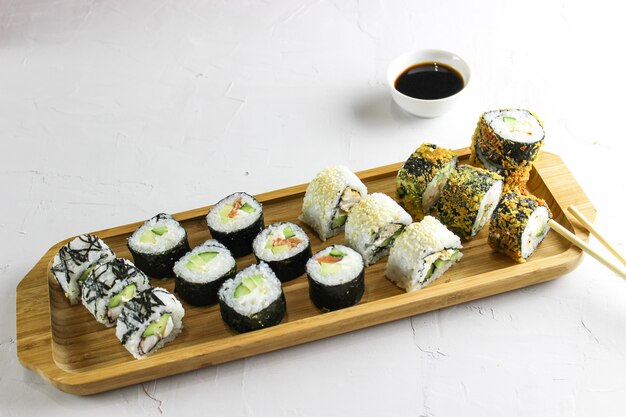 Sushi rolls on a wooden tray with soy sauce