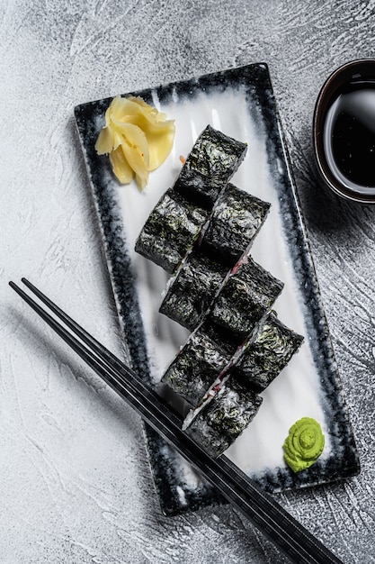Sushi rolt hosomaki met zalm, avocado en tonijn. grijze achtergrond. bovenaanzicht