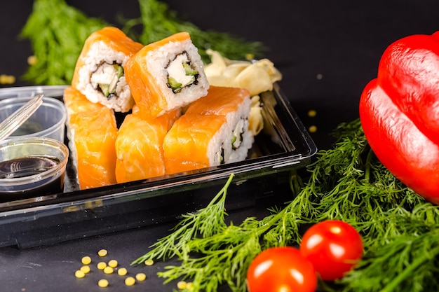 Sushi rolt Philadelphia ligt op een vierkante stenen leisteen, met muntblaadjes, wasabi en sojasaus, groen