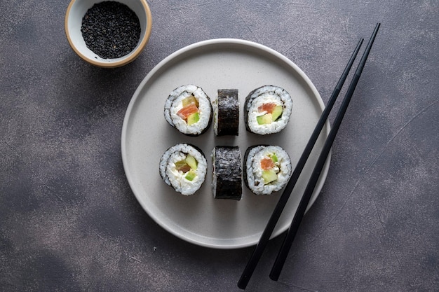 Sushi on round plate with chopsticks soy sauce ginger Homemade rolls with salmon avocado and cucumber