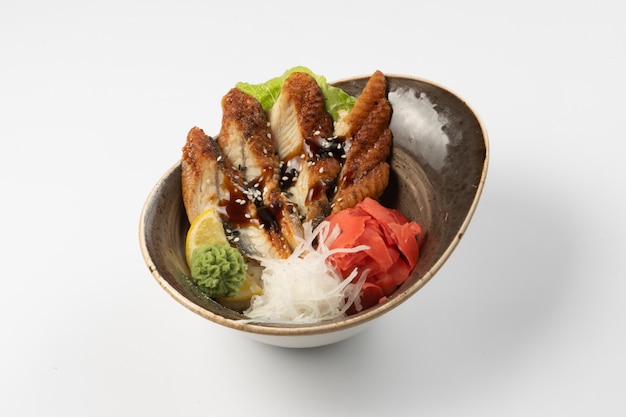 Sushi sashimi unagi. Plakjes paling in teriyakisaus met daikon radijs, gember, wasabi, sla en partje citroen op een rijstpad