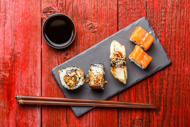 Sushi served on black board at red wooden table