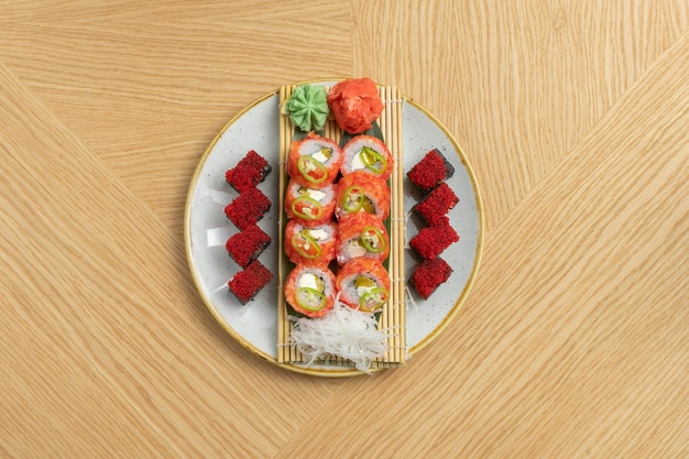 Sushi set of different rolls with tuna, salmon, shrimps, tobiko flying fish roe, ginger, daikon radish, black rice with cuttlefish and wasabi cherinles.