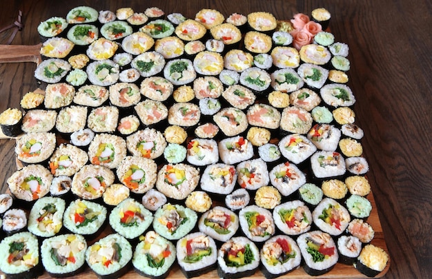 Суши-сет - различные виды маки суши и нигири суши. Подается на темном деревянном столе.