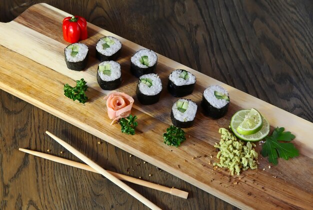 Sushi set - diversi tipi di maki sushi e nigiri sushi con bacchette di legno. servito su un tavolo di legno scuro in stile rustico.