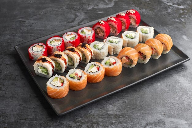 Sushi set Roll Philadelphia Tempura Zalm California Red met verse ingrediënten op stenen achtergrond