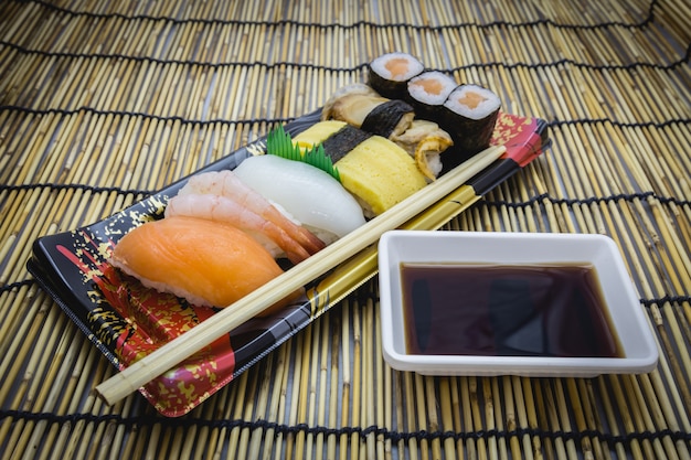 Sushi set sashimi en broodjes geserveerd op traditionele plaat en mat met shoyu Japans