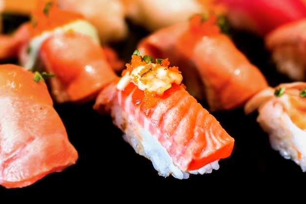 Sushi Set Sashimi and sushi rolls served on black stone slate with white background