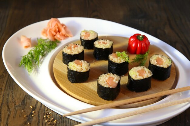 Sushi Set - Verschillende soorten Maki Sushi en Nigiri Sushi met houten eetstokjes. Geserveerd op donkere houten tafel op een rustieke stijl.