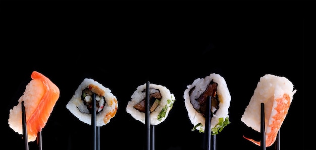 照片寿司用筷子套在黑色背景。空间的文本。背景菜单