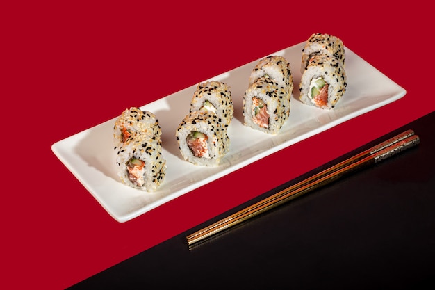 Sushi Sets Nigiri, Uramaki, California, Philadelphia, on a white plate. On a red colored background. Copy space.