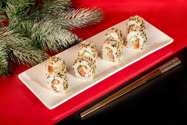 Sushi Sets Nigiri, Uramaki, California, Philadelphia, on a white plate. On a red colored background. Copy space.