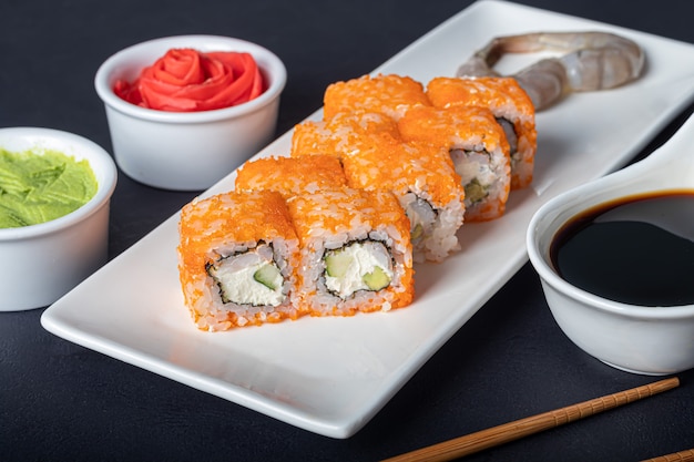 Sushi Sets Uramaki, California, Philadelphia, on a white plate. Nearby ginger and wasabi.