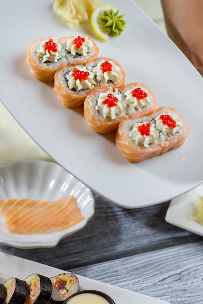 Суши и васаби с лимоном. Суши-роллы, лежащие на тарелке. Новое японское блюдо в меню. Роллы Урамаки с невероятным вкусом.