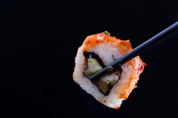 Sushi with black chopsticks on black background