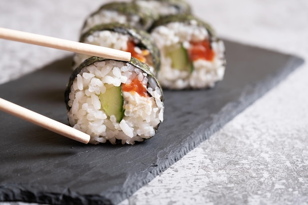 Sushi with chopsticks on a black slate board