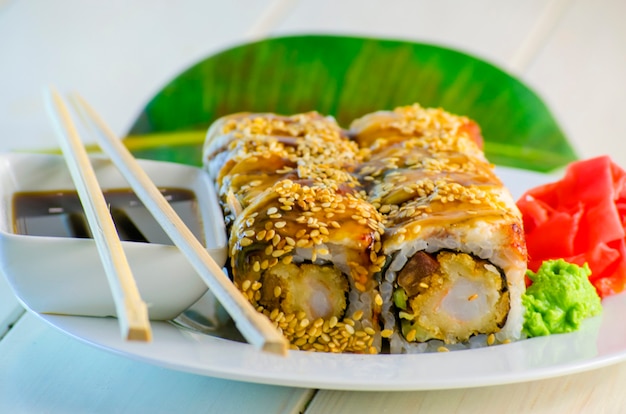 Sushi with eel and shrimp tempuro on a plate and a white background