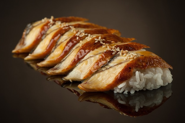 Sushi with rice and sesame seeds on a dark background with reflection