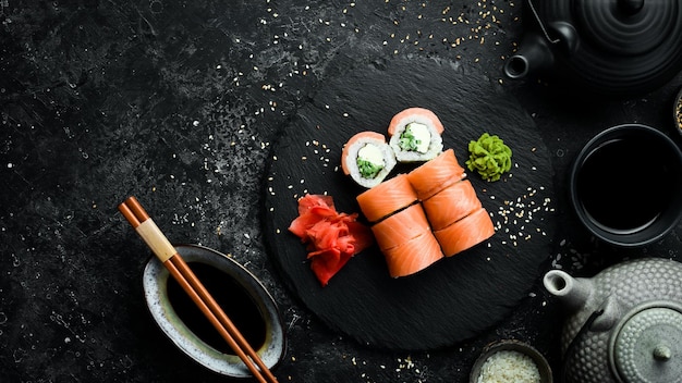 Sushi with salmon and Philadelphia cheese Traditional Japanese food On a black stone plate Top view