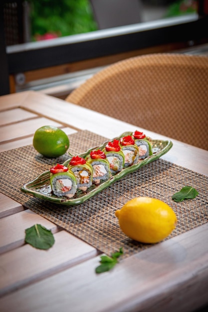 Sushibroodjes met kaassaus, aardbeien en zalm op een houten tafel op het zomerterras van het restaurant