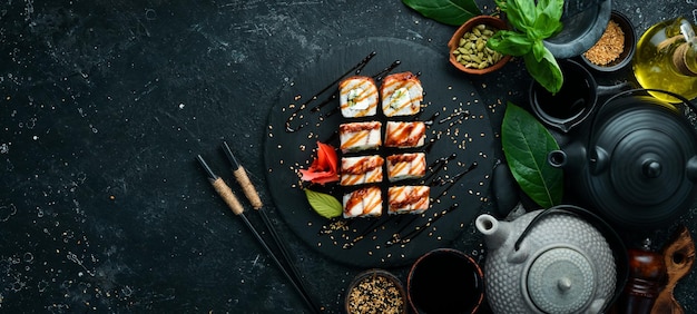 Sushibroodjes met palingkomkommer en kaas op een zwarte steenplaat Japanse keuken Bovenaanzicht