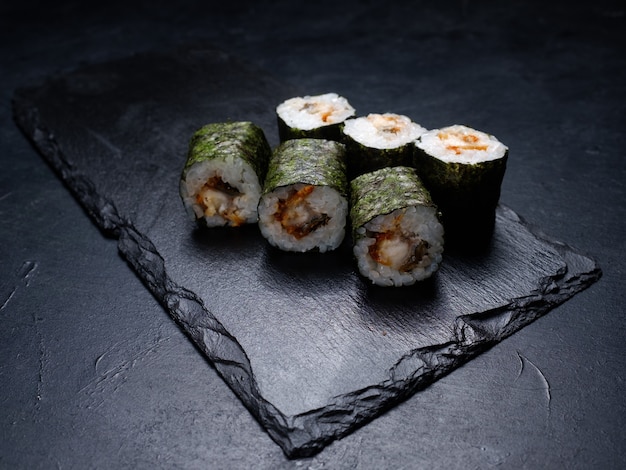 Sushibroodjes met zalm bedekt met nori op donkere achtergrond. Japanse traditionele gerechten voor het bereiden van gerechten