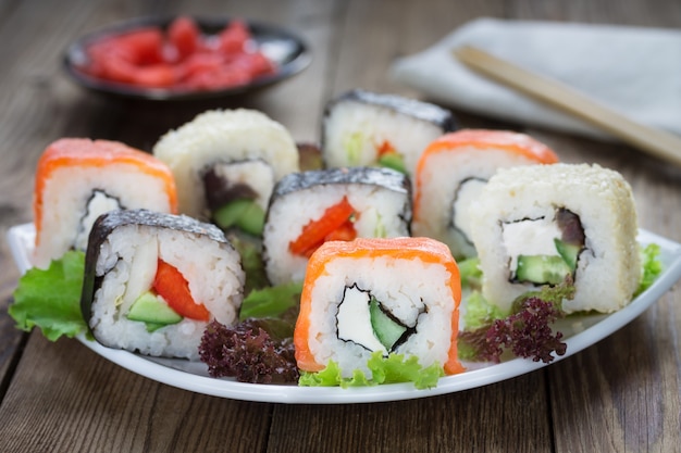 Sushibroodjes op een witte plaat met gember en een keukenservet.